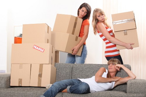 Movers using proper lifting techniques with a trolley and straps